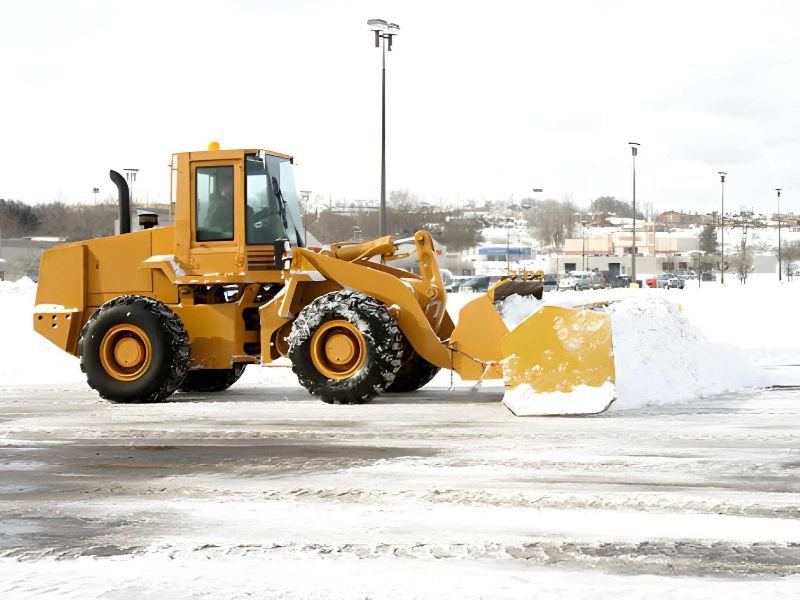A wheel loader clearing snow from a lot.