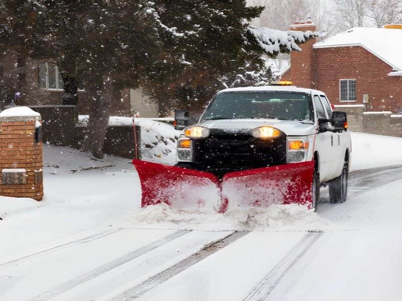 A pickup truck plowing snow on a street.