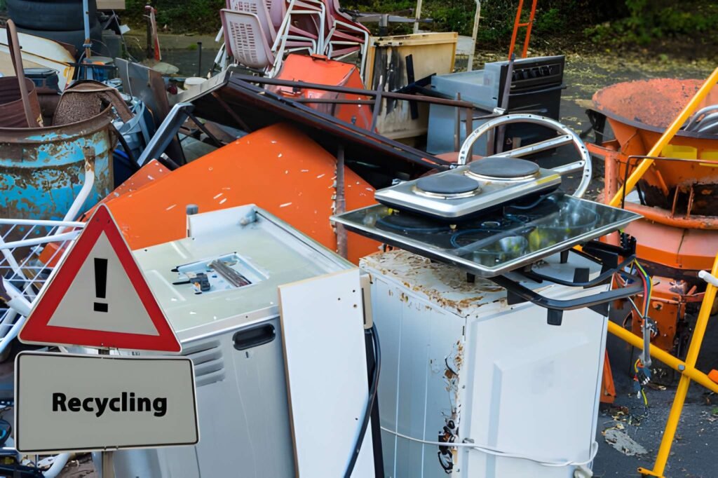 A pile of discarded appliances with a recycling sign.