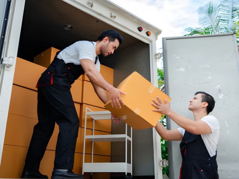 Two movers unloading boxes from a truck.