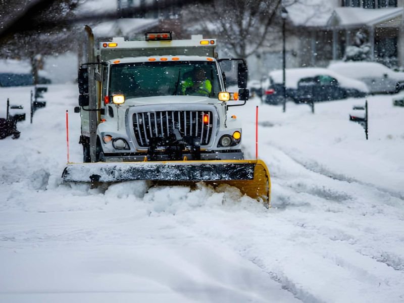 A snow plow clearing a residential street.