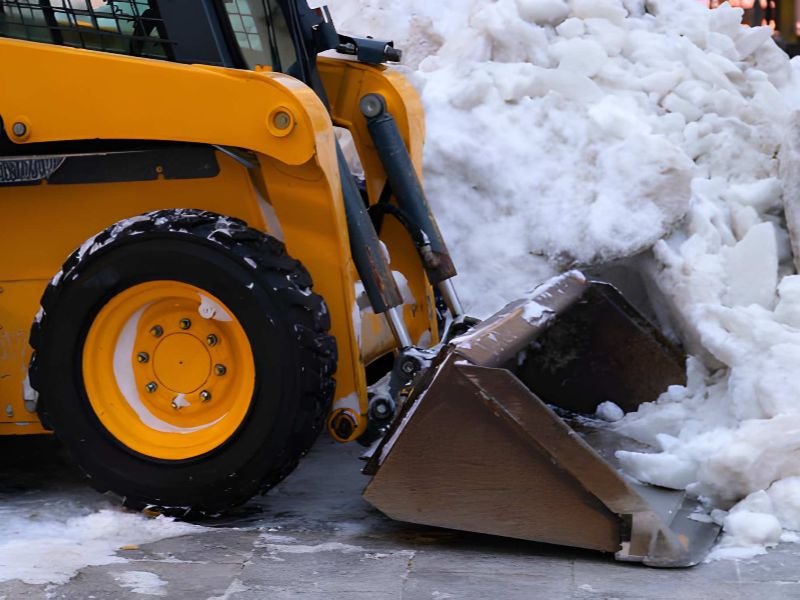 A skid steer loader moving snow piles.